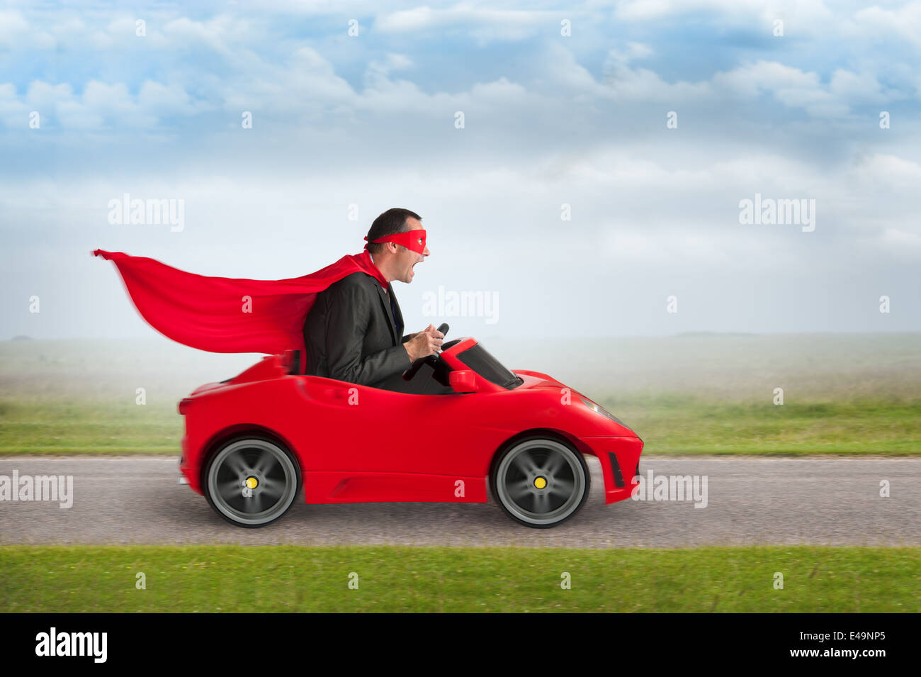 Superheld Mann fahren ein rotes Spielzeugauto Racing mit Geschwindigkeit Stockfoto