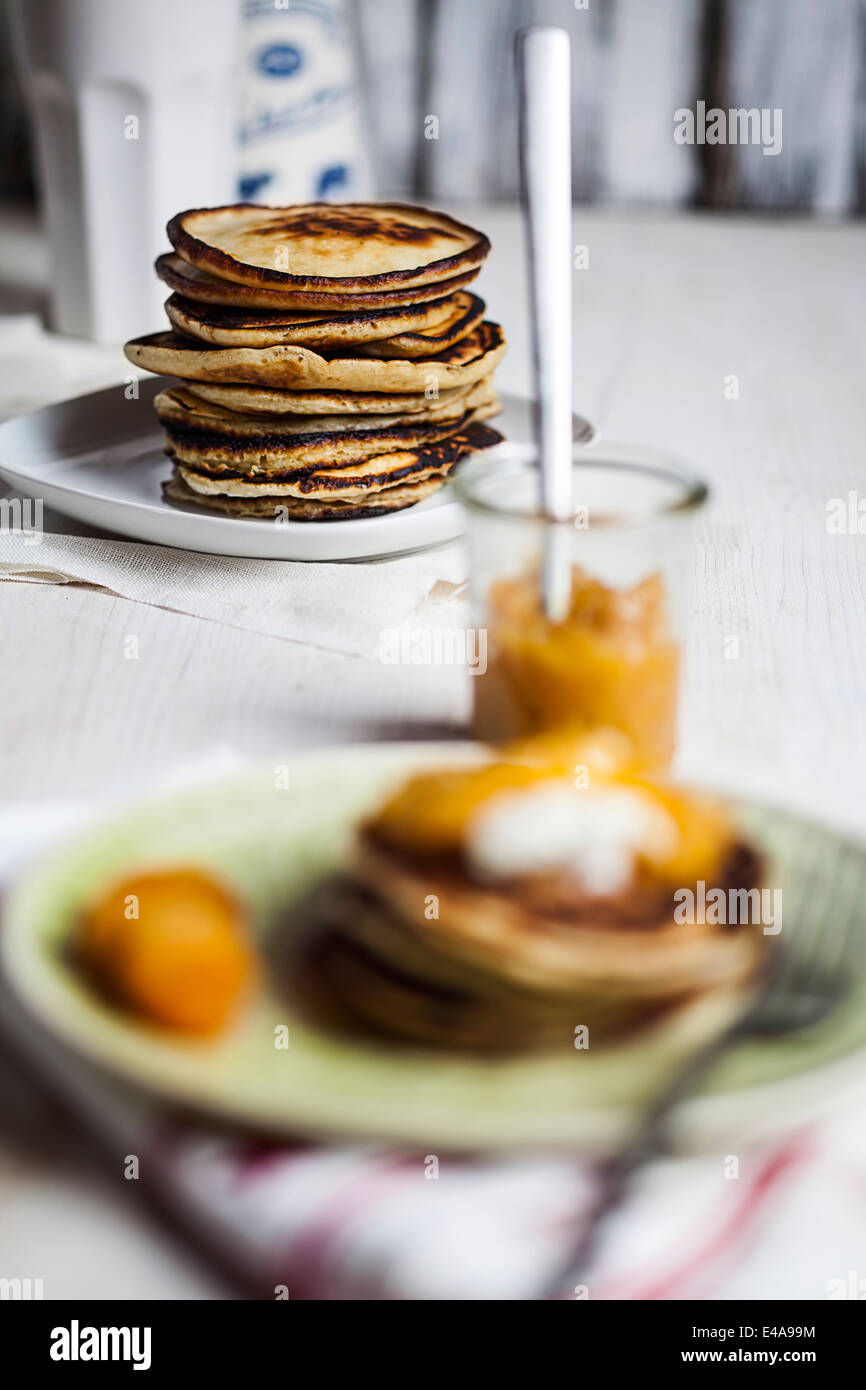 Stapel von amerikanische Pfannkuchen und Glas Aprikosen-Sauce auf Tisch Stockfoto