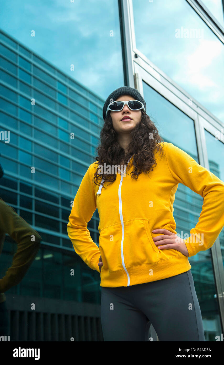 Junge Frau trägt gelbe Anzug-Jacke, Mütze und Sonnenbrille Stockfoto