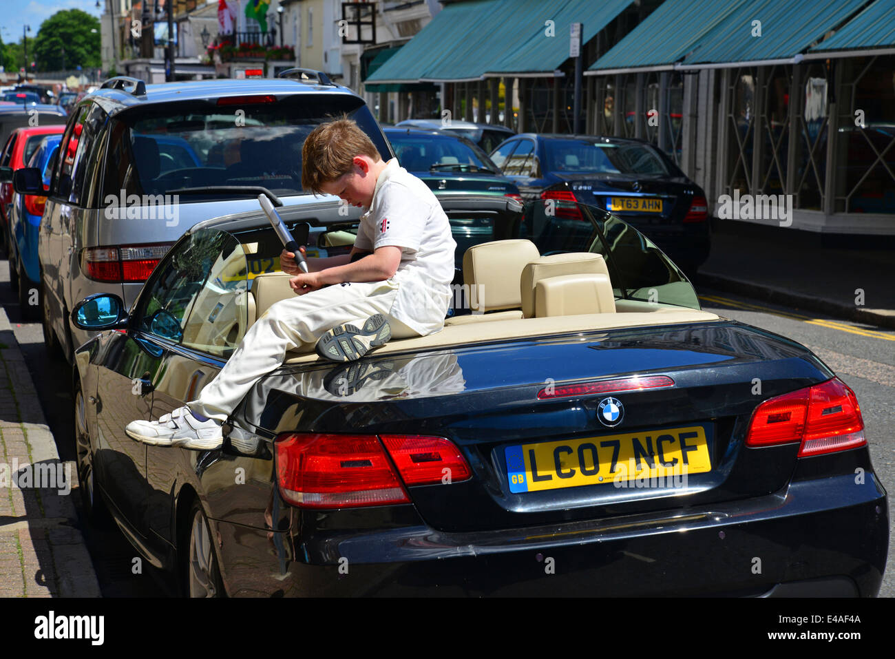 Junge sitzt auf Auto, Bridge Street, East Molesey, Surrey, England, Vereinigtes Königreich Stockfoto
