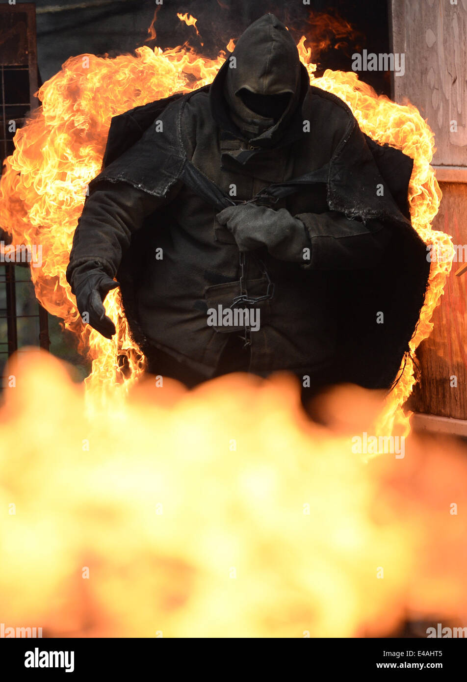 Ein Stuntman in Brand führt quer durch die sogenannte Vulkan Arena während einer Stuntshow im Studio Babelsberg in Potsdam, Deutschland, 7. Juli 2014. Die Stunt-Arena wurde vor 15 Jahren gebaut und wurde bis zu 3.333 Shows mit mehr als 5 Millionen Besucher seit dieser Zeit zeigt. Foto: Ralf Hirschberger/dpa Stockfoto