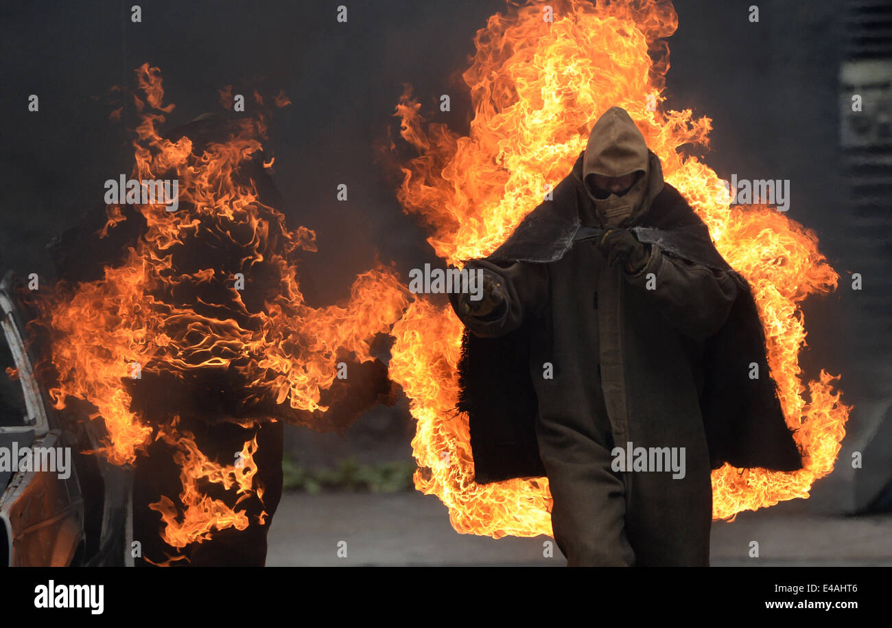 Stunt-Männer auf Feuer läuft über die so genannte Vulkan Arena während einer Stuntshow im Studio Babelsberg in Potsdam, Deutschland, 7. Juli 2014. Die Stunt-Arena wurde vor 15 Jahren gebaut und wurde bis zu 3.333 Shows mit mehr als 5 Millionen Besucher seit dieser Zeit zeigt. Foto: Ralf Hirschberger/dpa Stockfoto