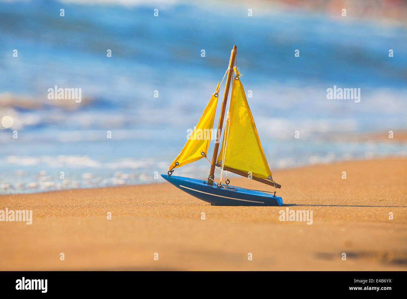 Das kleine Spielzeugboot steht am Sandstrand Stockfoto