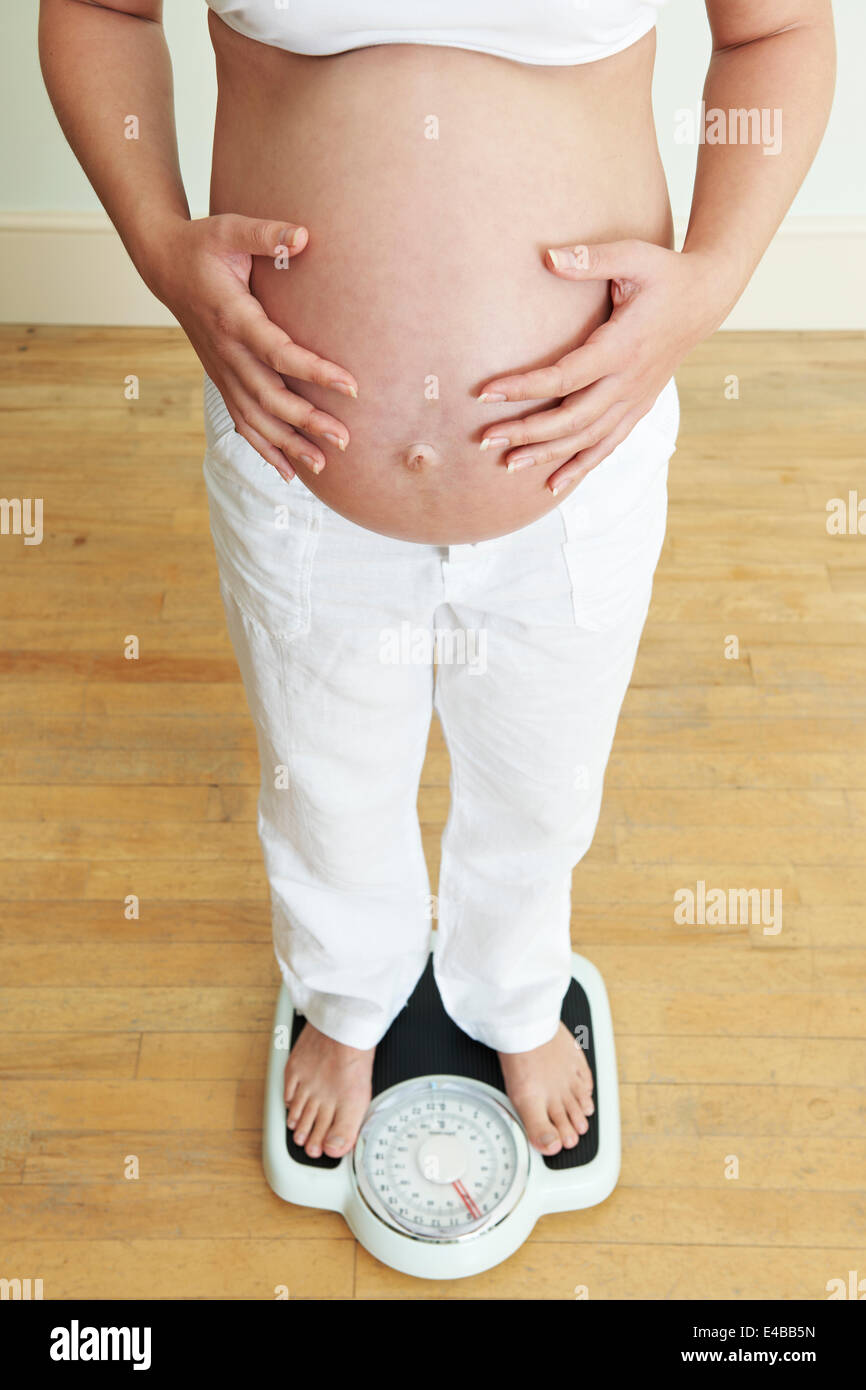 Schwangere Frau auf Personenwaage Stockfoto