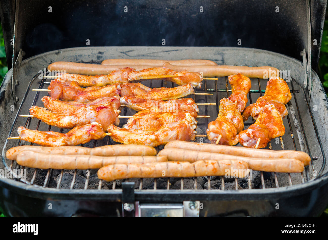 Würstchen und Chicken Wings auf das Rauchen grill barbeque Stockfoto