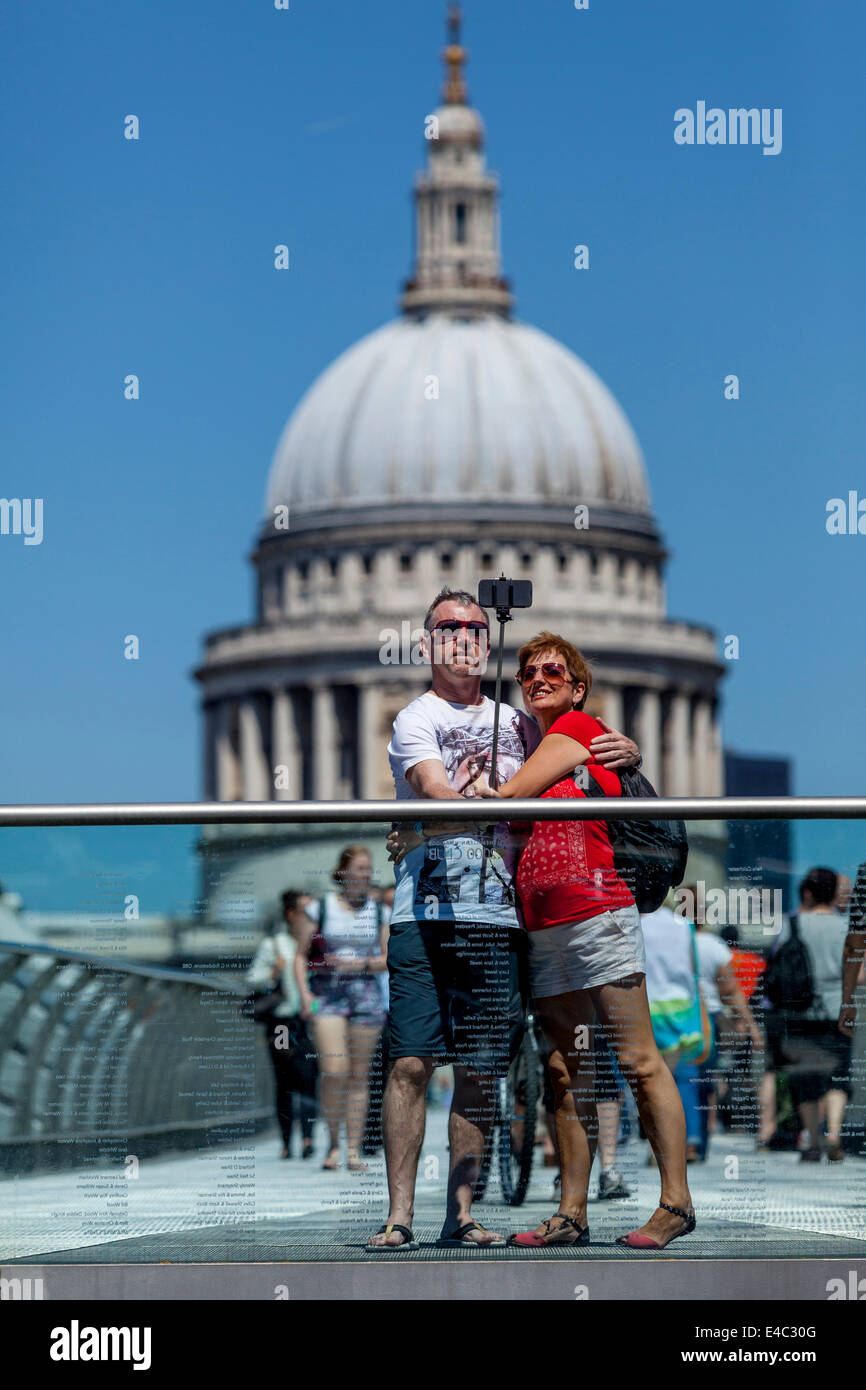 Ein paar Fotografieren selbst (Selfie) auf The Millennium Bridge mit St. Pauls Kathedrale In den Hintergrund, London, England Stockfoto