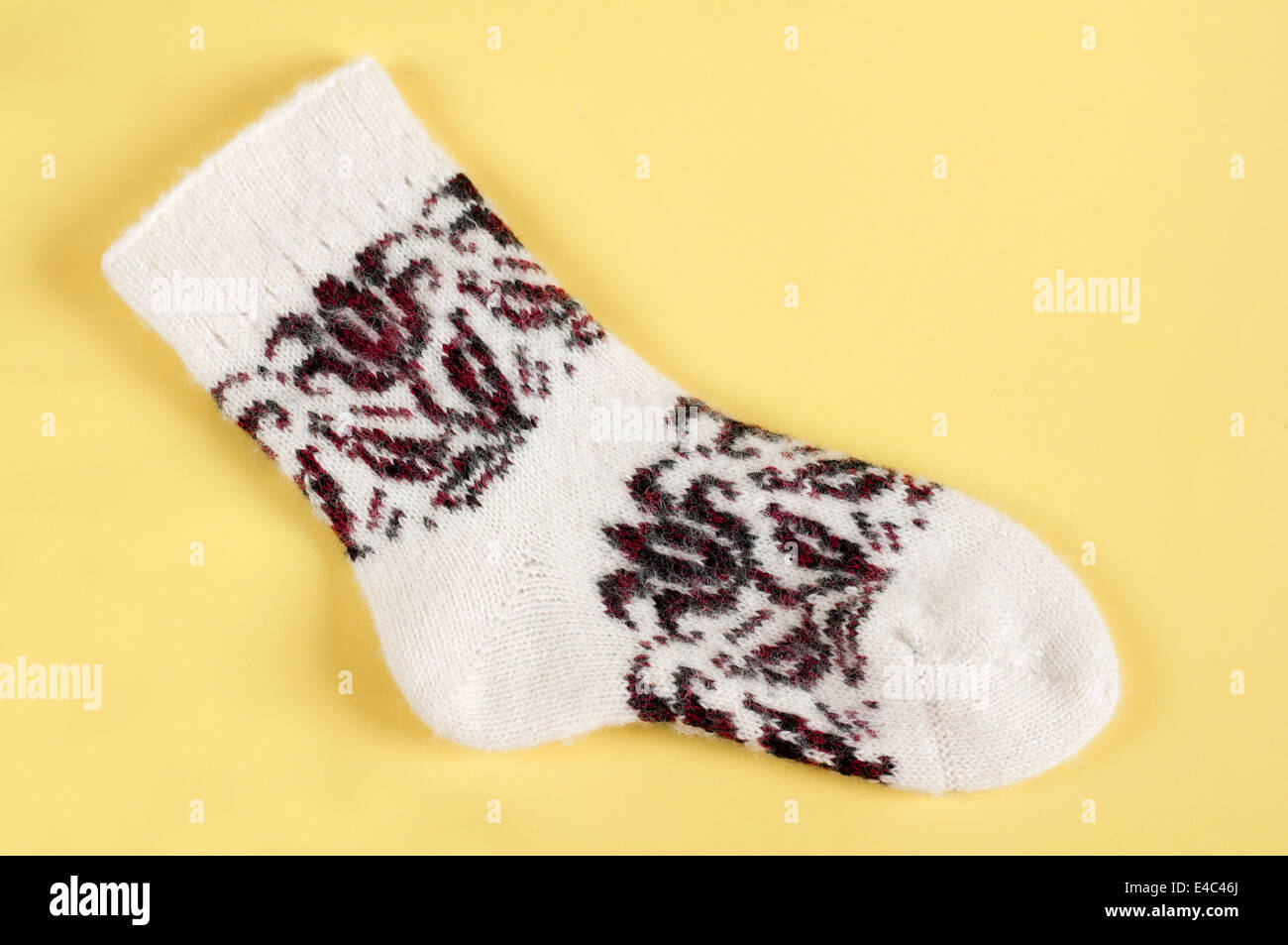 Socken gestrickt aus Wolle Wolle warm weiße Muster Ornament Kleidung Handarbeiten stricken. Hintergrund gelb niemand winter Stockfoto