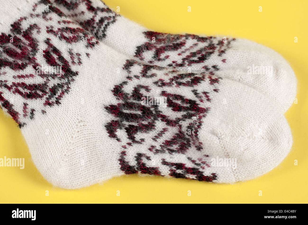 Socken gestrickt aus Wolle Wolle warm weiße Muster Ornament Kleidung Handarbeiten stricken. Hintergrund gelb niemand winter Stockfoto