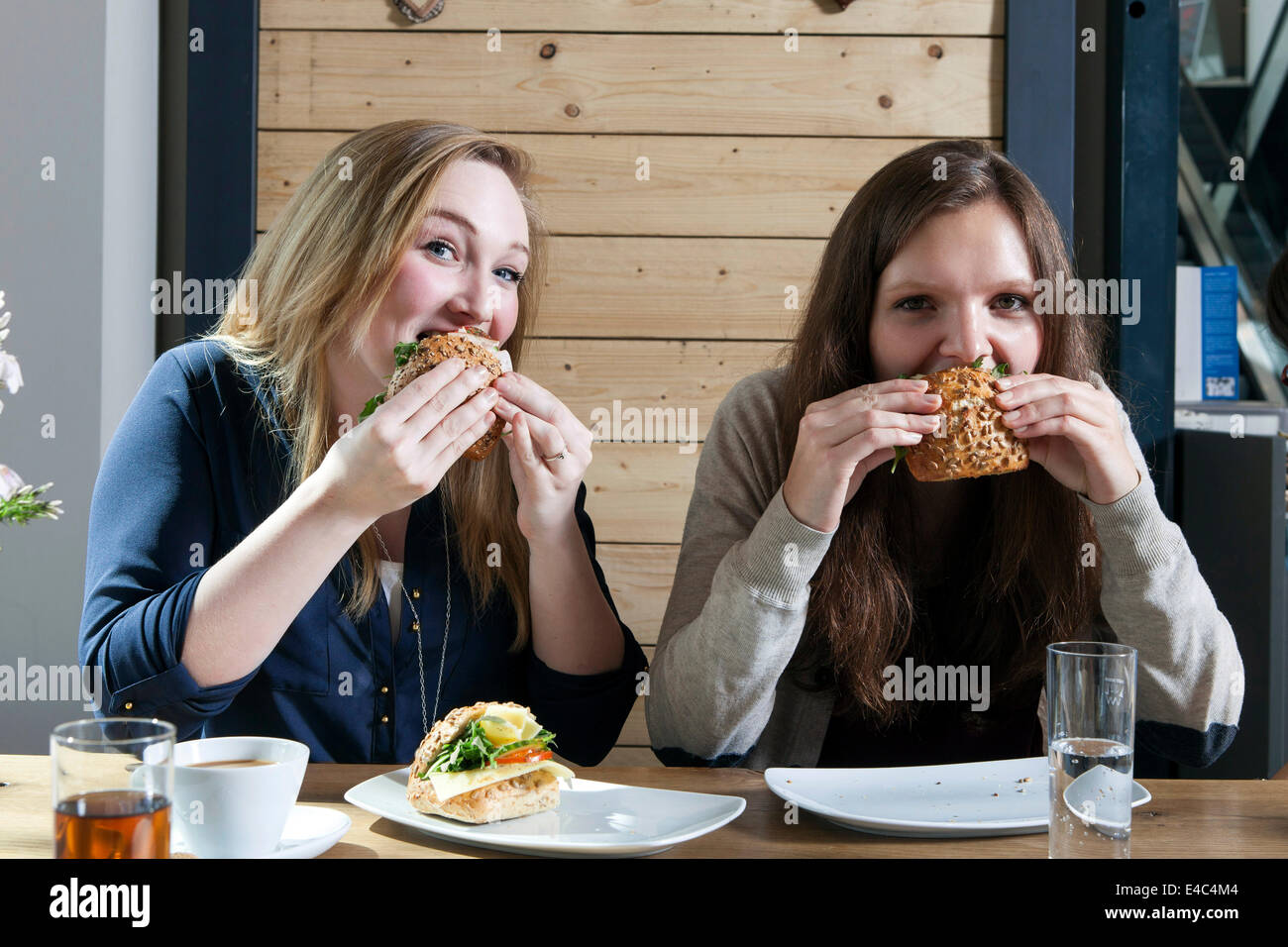 Zwei junge Frauen Essen Sandwiches in einem café Stockfoto