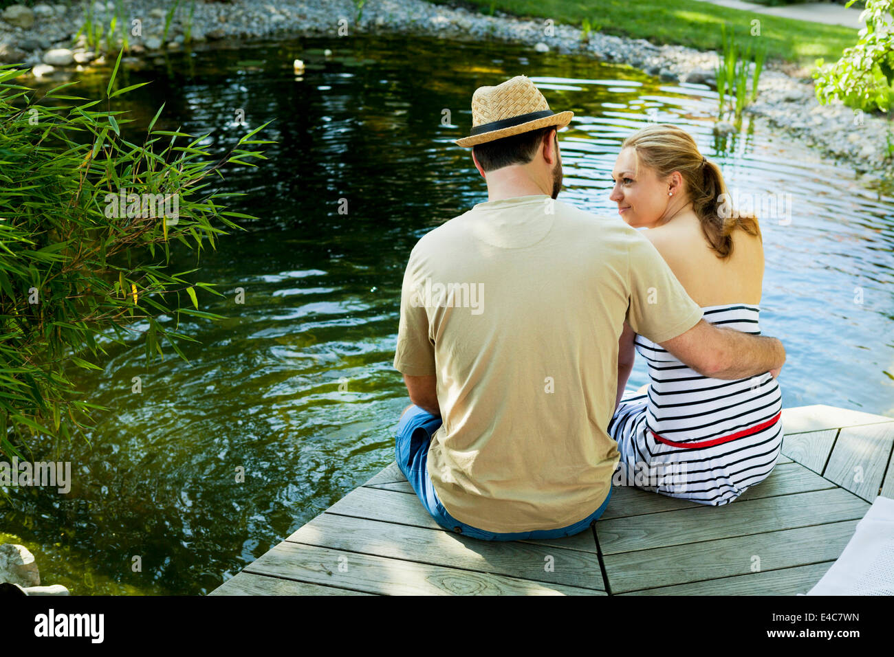 Heterosexuelles Paar nimmt sich eine Auszeit am Teich, Rückansicht, München, Bayern, Deutschland Stockfoto