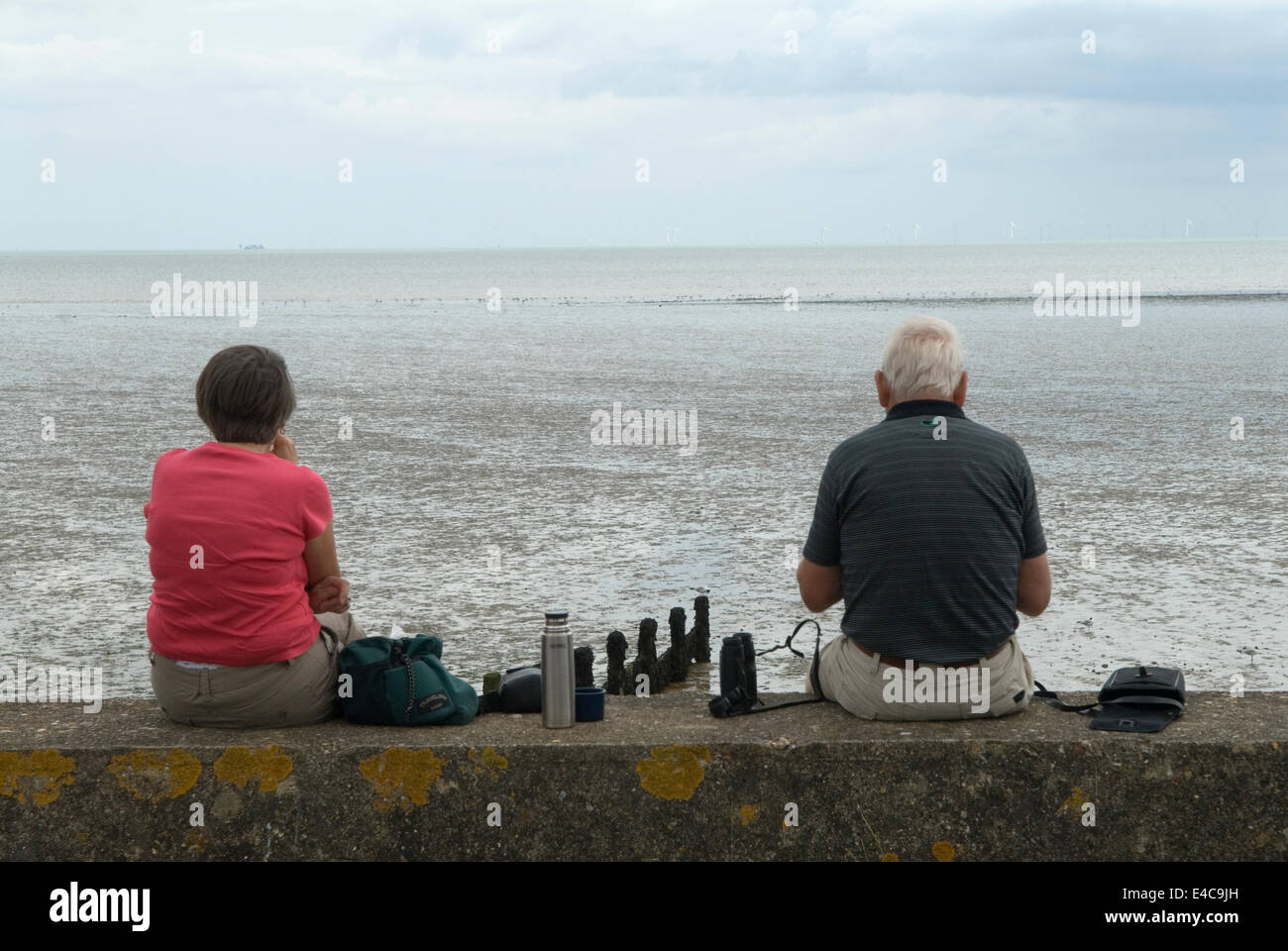 Pensionierte Paar, vertraut miteinander und sitzt auseinander, Thermoskanne genießen Tag an der Küste Isle of Sheppey Kent 2014 2010s UK. HOMER SYKES Stockfoto