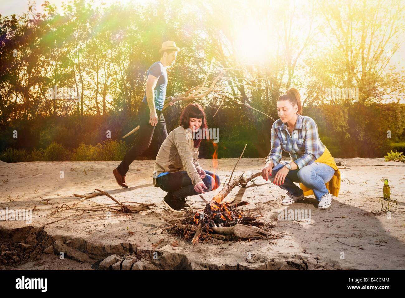 Gruppe von Freunden, die Vermittlung von Brennholz am Lagerfeuer, Osijek, Kroatien Stockfoto