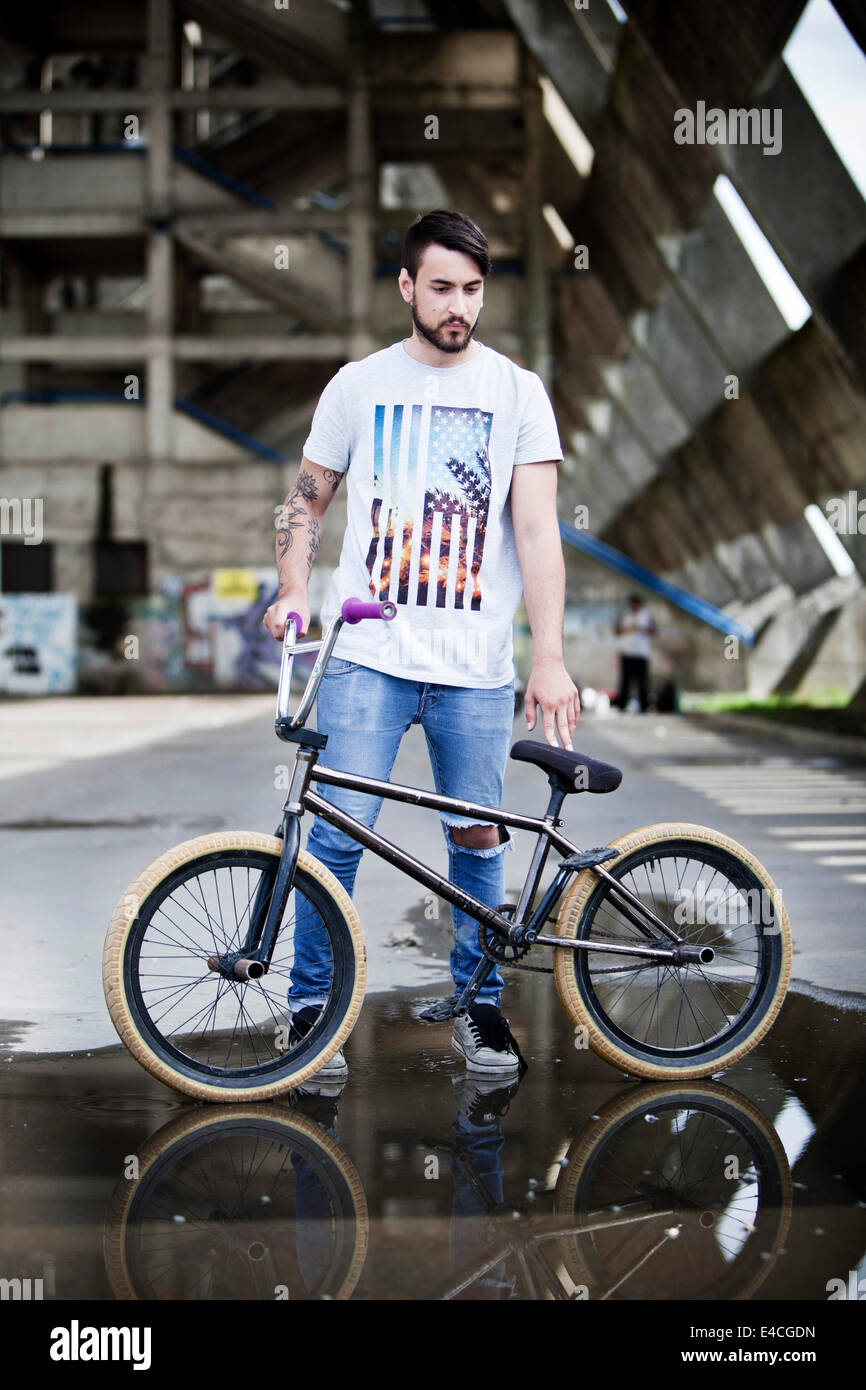 Junger Mann mit BMX Fahrrad stehen in einer Fabrikhalle Stockfoto
