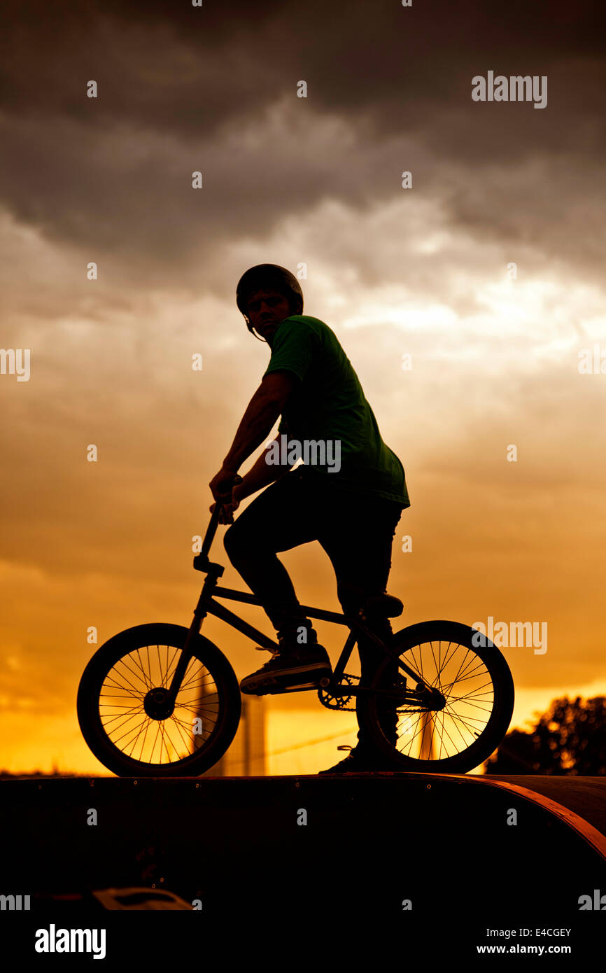 BMX-Biker mit Fahrrad stehend gegen Sonnenuntergang Stockfoto