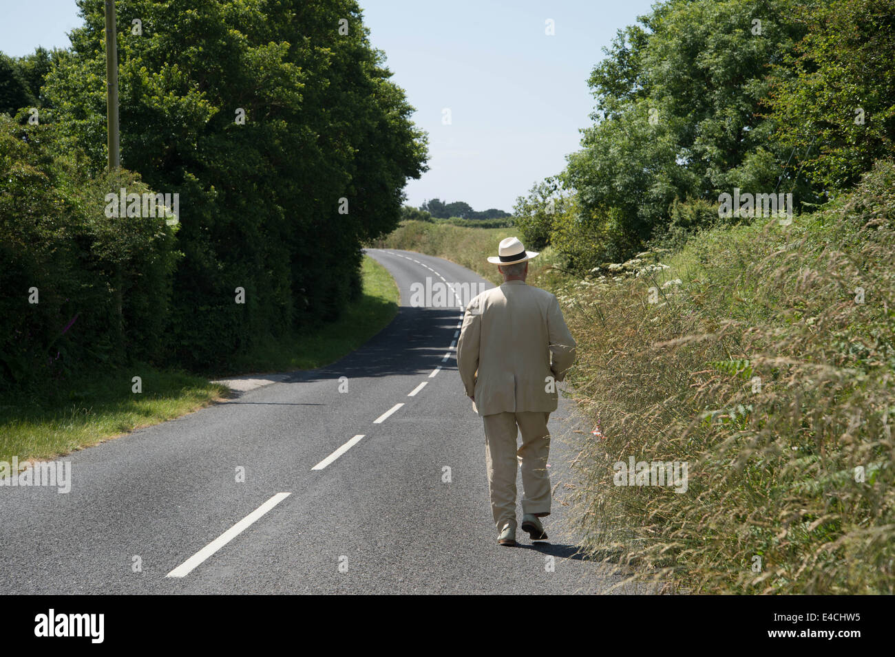 Cornwall. Roseland Halbinsel. Mann in einem weißen Anzug und einem Panama-Hut einen Feldweg hinunter. Stockfoto