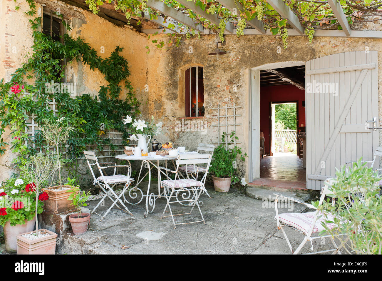 Schmiedeeisen Tisch und klappbare Bistro Stühle in Hof mit obenliegenden Spalier und Weinrebe Stockfoto