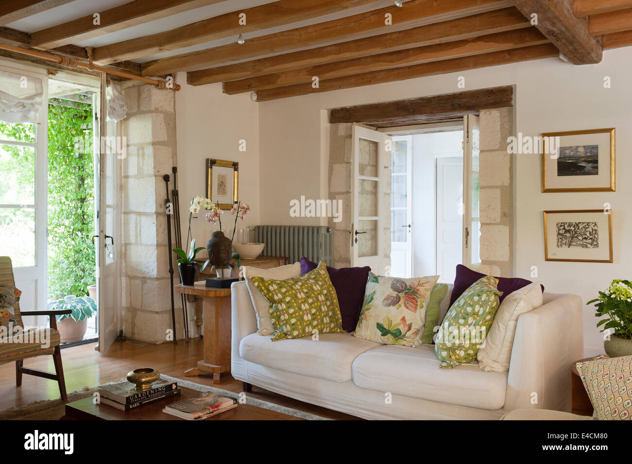 Weißes Sofa im Wohnzimmer mit Holzbalken und Steinmauer Detail. Die Kissen werden von Kate Armitage aus Vintage f hergestellt. Stockfoto