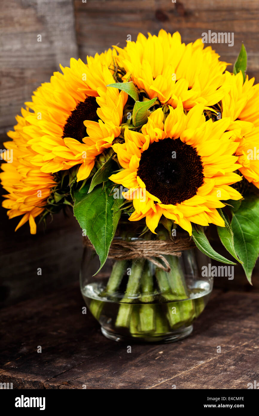 Schöne frische Sonnenblumen in Vase auf hölzernen Hintergrund ...