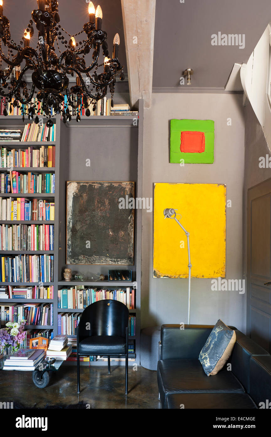 Schwarze Ledercouch im Wohnzimmer mit Bookshelving, Kandelaber Chrom und schwarz Corbusier Stuhl sowohl aus Le Pigeon d ' or Stockfoto