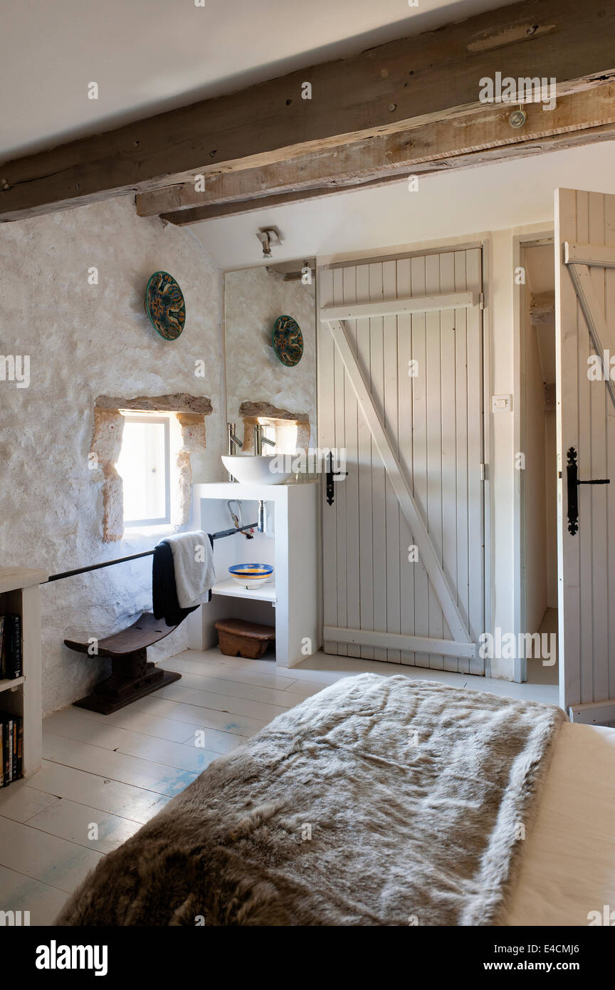 Stein eingemauert Schlafzimmer mit hölzernen Balkendecke, Waschtisch und Fell werfen auf Bett Stockfoto