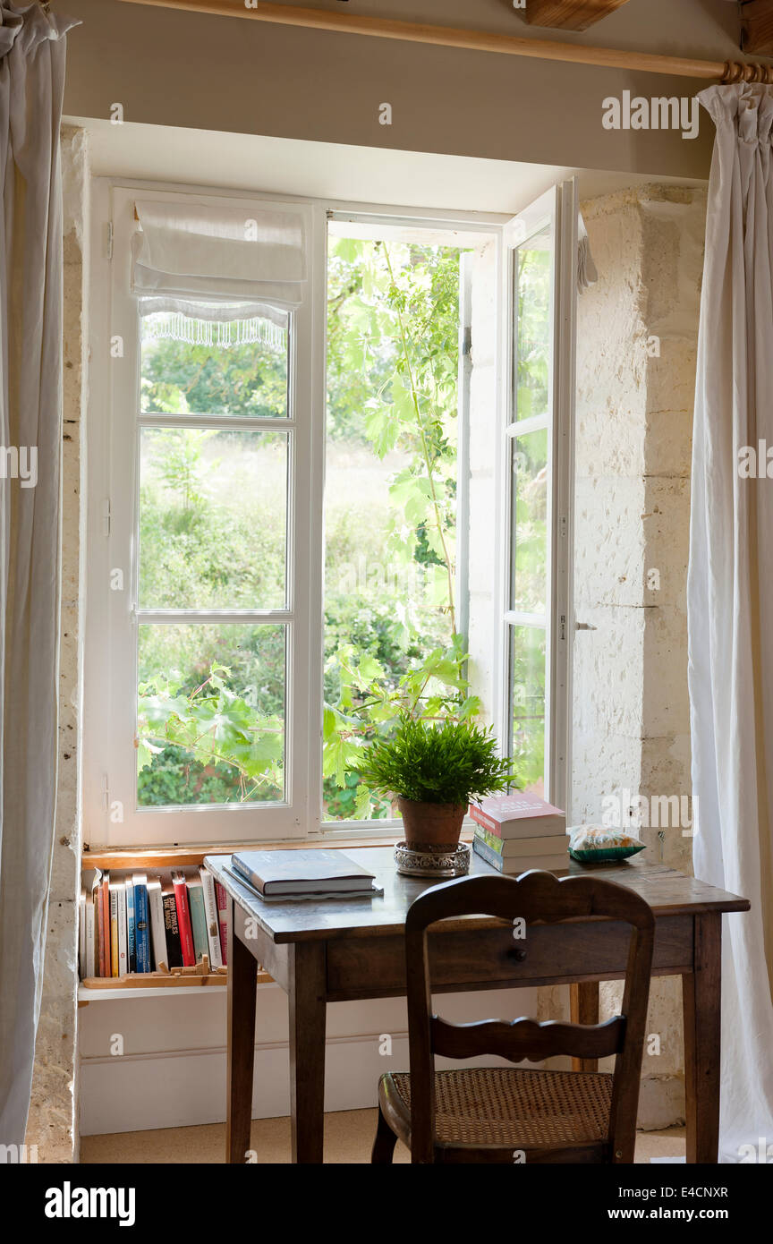 Französischer Eichentisch und antiken Stuhl durch Fenster mit Blick auf den Garten Stockfoto