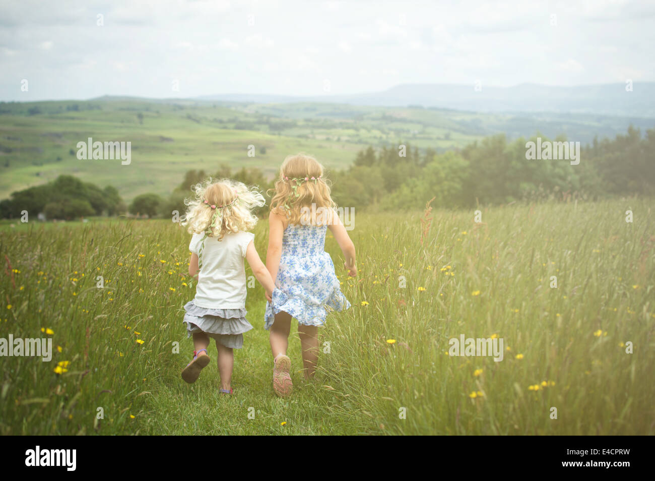 2 Schwestern laufen über eine Blumenwiese Stockfoto