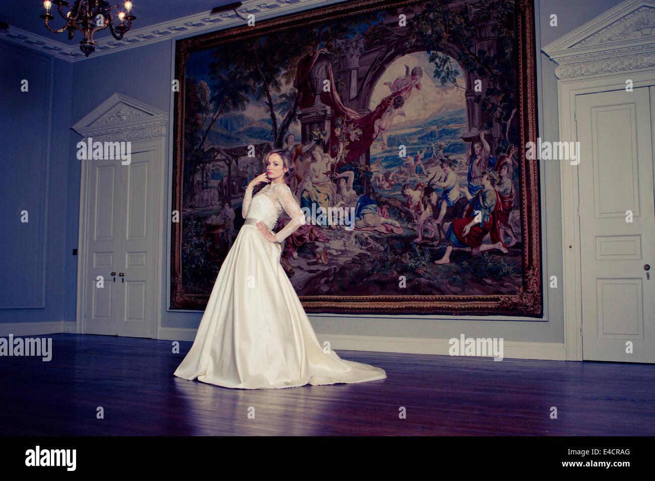 Braut steht mit der Hand auf die Hüfte gegen riesige Gemälde, Dorset, England Stockfoto