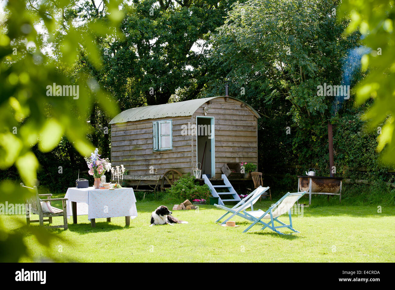 Eine hausgemachte Hirten-Hütte in einem englischen Landhaus-Garten mit Liegestühlen Stockfoto
