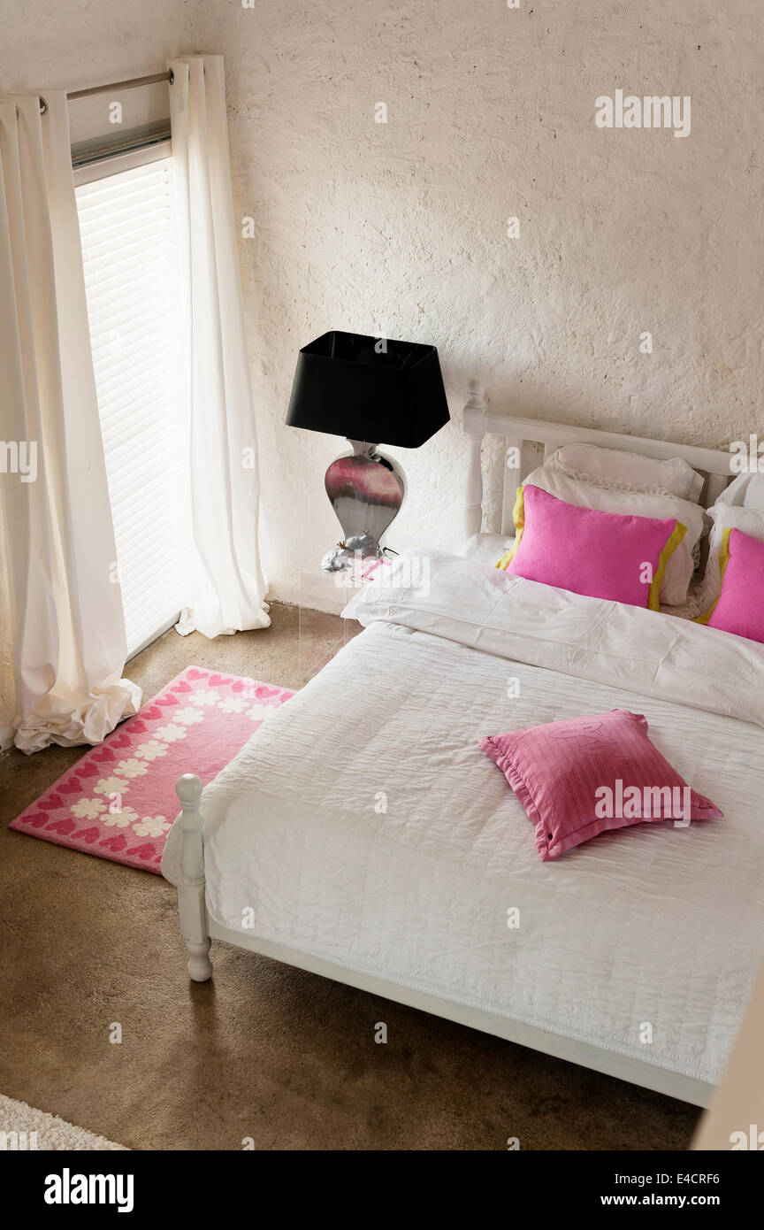 Rosa Kissen auf weißen Bett im Schlafzimmer mit Rosa Teppich Stockfoto