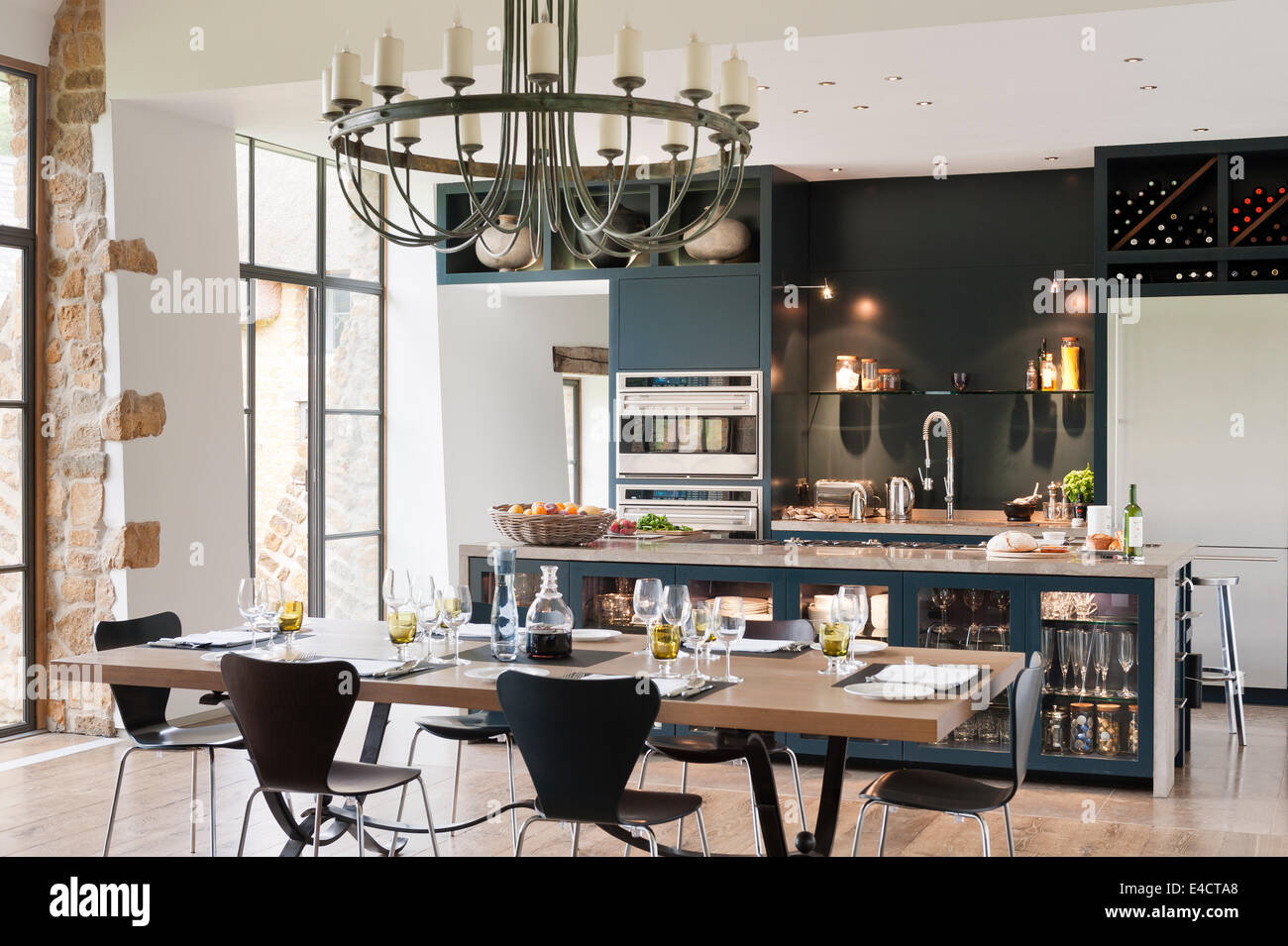 Grünspan-Kronleuchter hängt über einer Eiche gekrönt Esstisch in der Wohnküche mit Einheiten in blau/grau lackiert Stockfoto