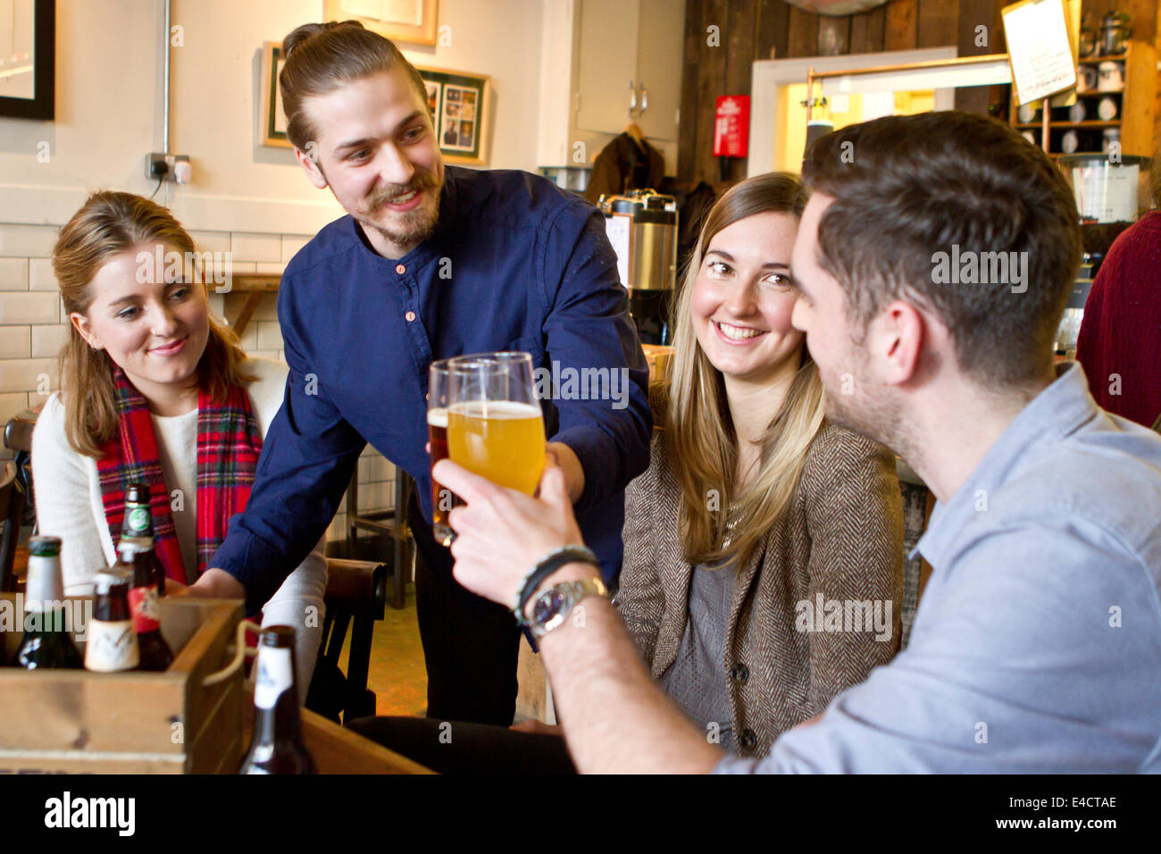 Junge Männer Toasten mit Bier in der Kneipe, Bournemouth, Dorset, England Stockfoto