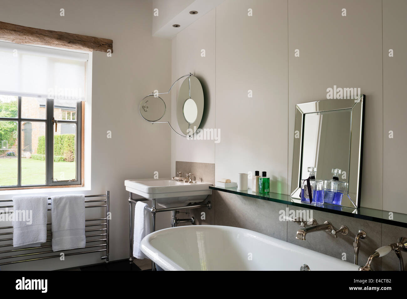 Roll Top Bad im weißen Badezimmer mit Glasablage und Spiegel Stockfoto