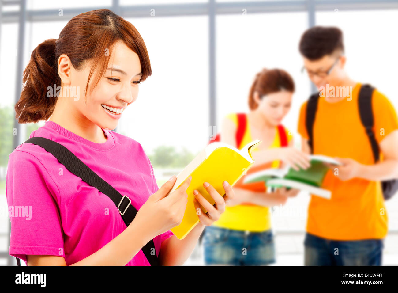 junge Studentin lesen mit Klassenkameraden in der Schule ein Buch Stockfoto