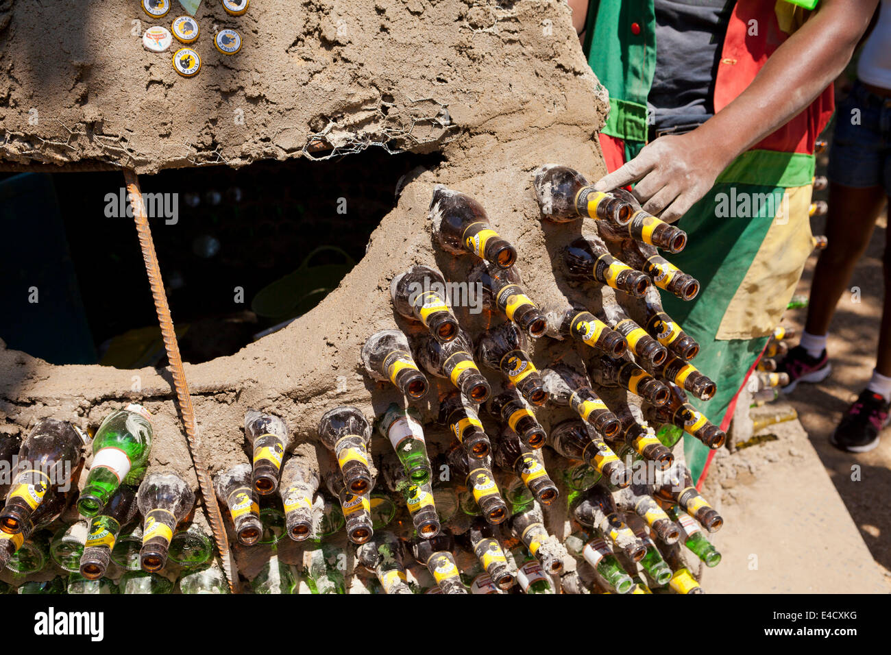 Kenianischen Mann Aufbau einer Lehmhütte mit Glasflaschen und andere Recycling-Materialien Stockfoto