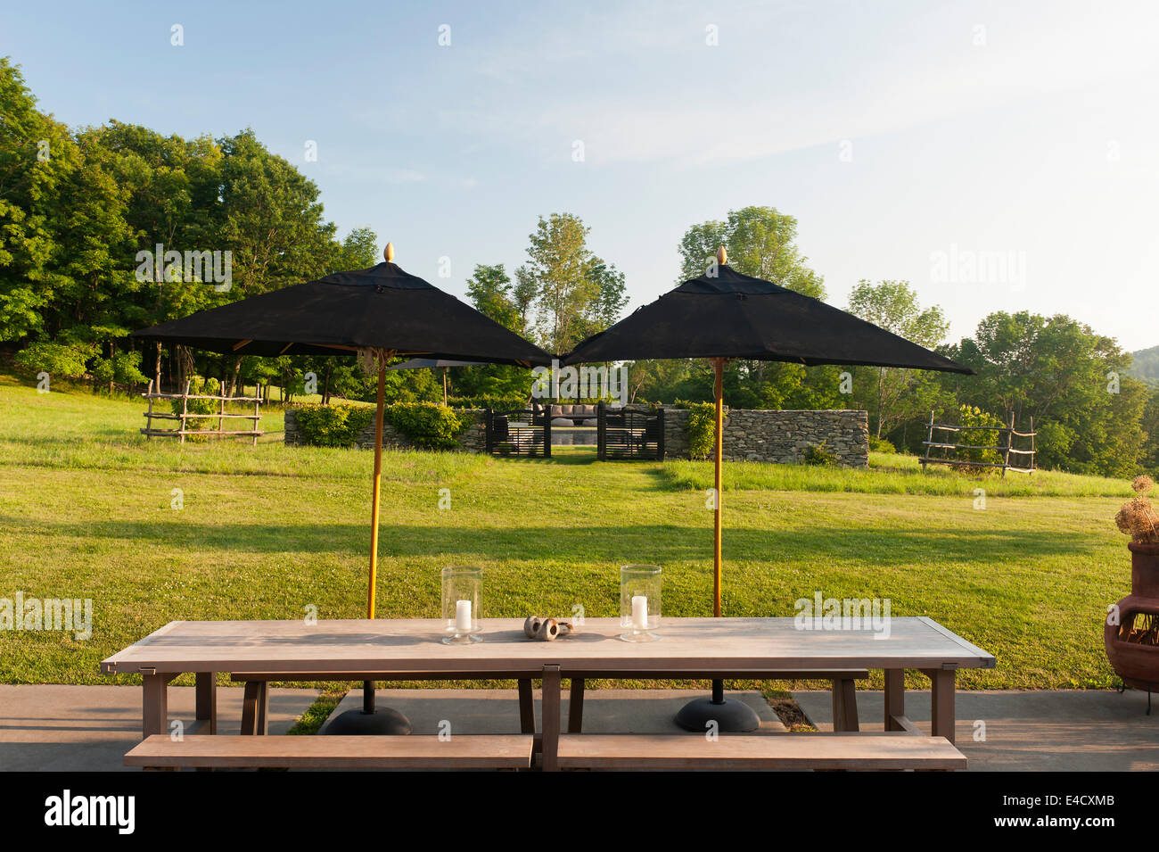 Schwarzen Sonnenschirme auf der Terrasse mit Tisch und Bank und Gartenblick Stockfoto