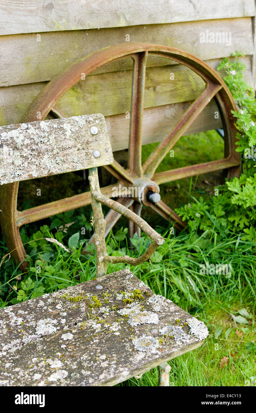 Ecke des alten Holzbank mit alten Eisenrad im Hintergrund Stockfoto