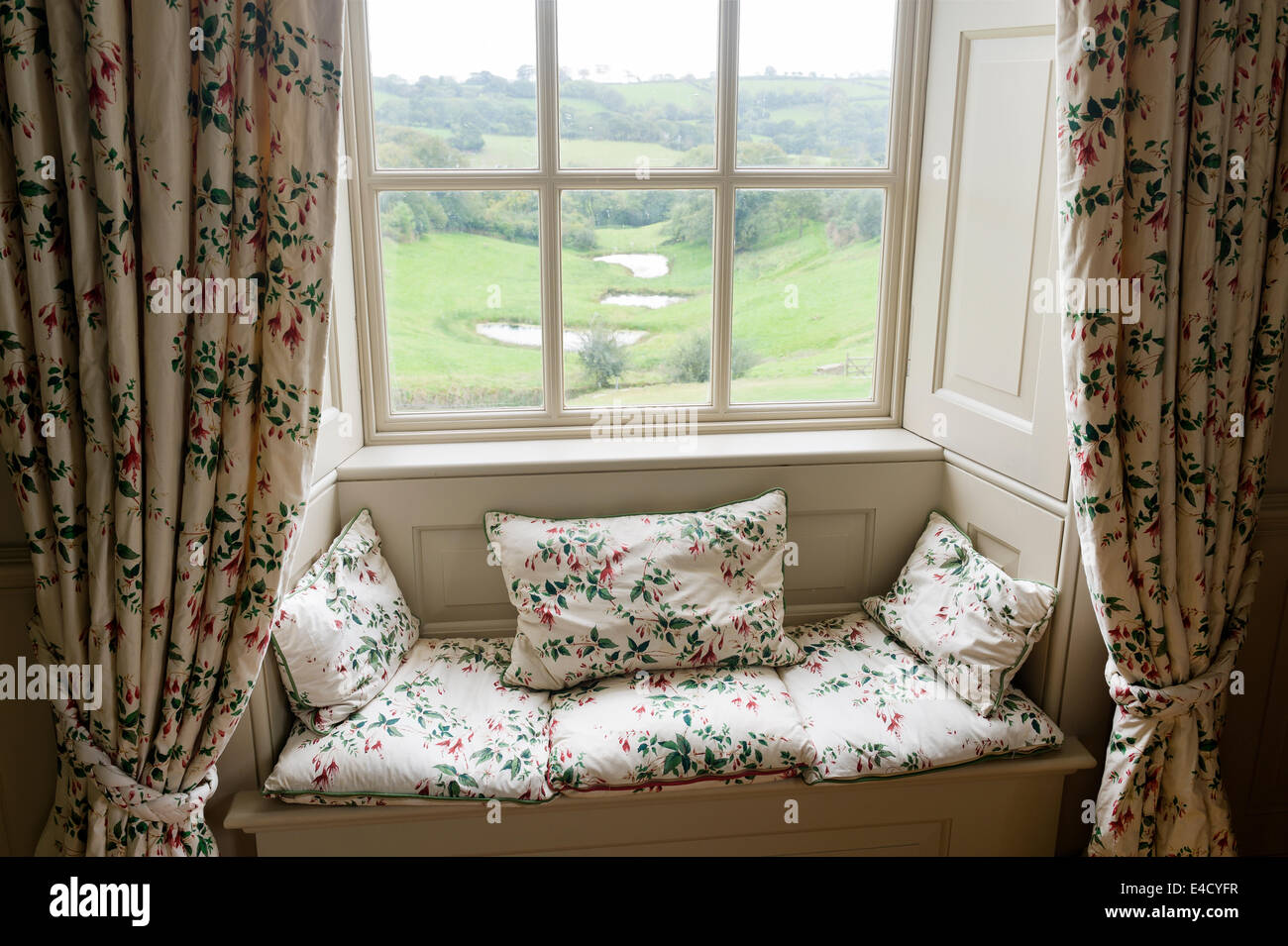 Einen gepolsterten Fensterplatz mit Blick auf ländliche Devonshire. Der Vorhang und Kissen Stoff ist von Colefax und Fowler Stockfoto