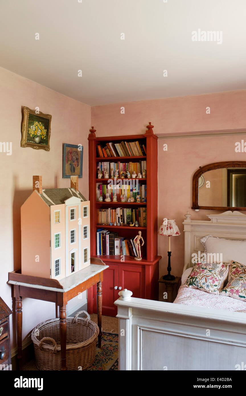 Altes Puppenhaus auf Marmor Top Waschtisch im Schlafzimmer mit roten Buch Regal und weiß Holzbett Stockfoto
