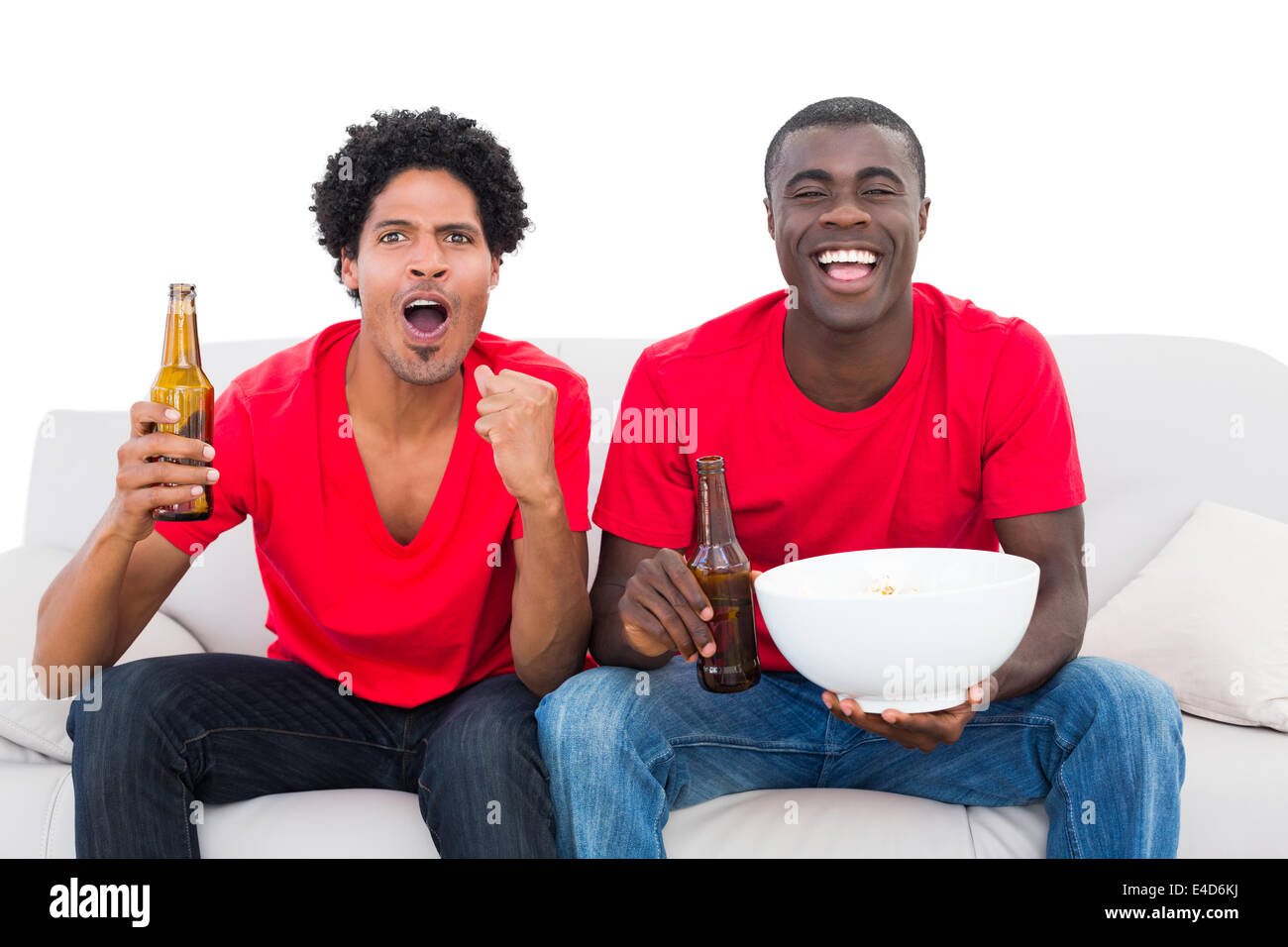 Fußball-Fans in rot jubeln auf der Couch mit Bier und popcorn Stockfoto