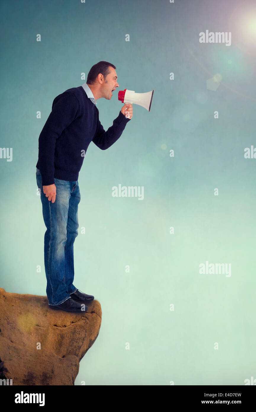 Mann mit einem Lautsprechergehäuse, Megaphon oder Megaphon schreien vom Rand einer Klippe Stockfoto