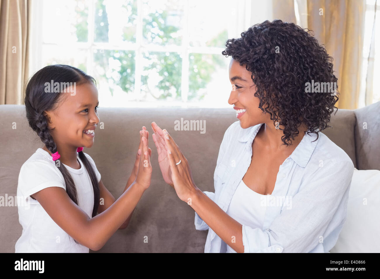 Ziemlich Mutter spielen, Händeklatschen Spiel mit Tochter auf couch Stockfoto