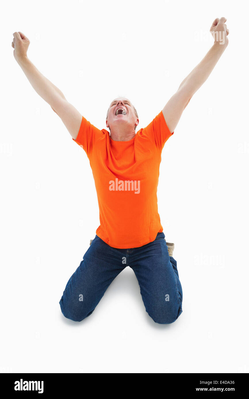 Reifer Mann in orange Tshirt kniend jubeln Stockfoto Reifer Mann in orange Tshirt kniend jubeln Stockfoto