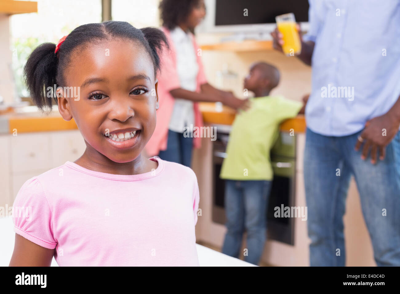 Niedliche kleine Mädchen lächelnd in die Kamera mit Familie im Hintergrund Stockfoto