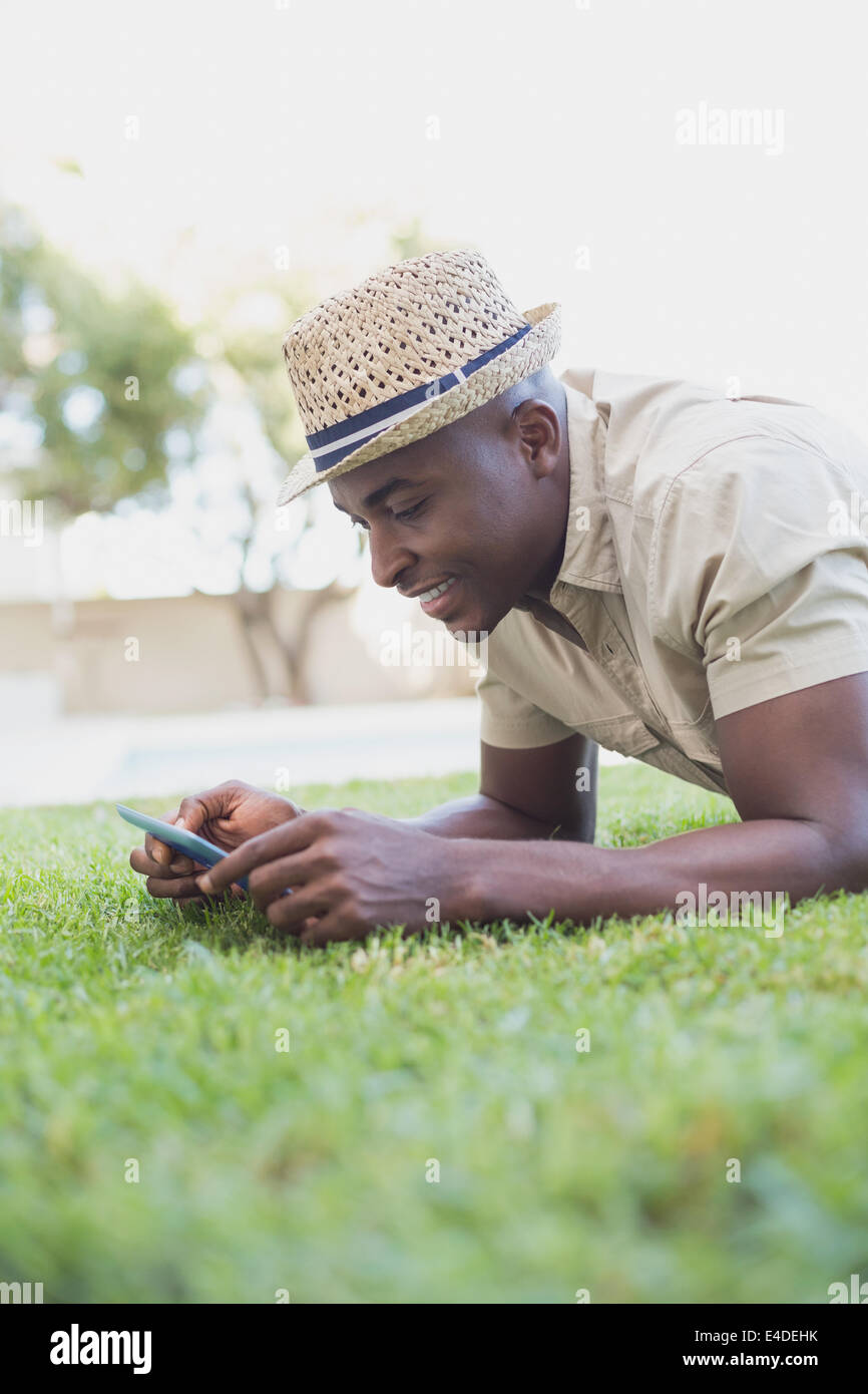Lächelnder Mann Entspannung in seinem Garten SMS auf Handy Stockfoto