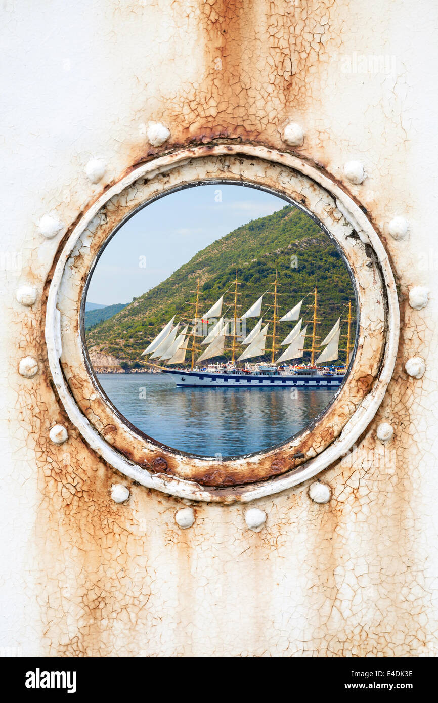 Großes Segelschiff hinter Runde verrosteten Bullauge auf weißen Wand Stockfoto