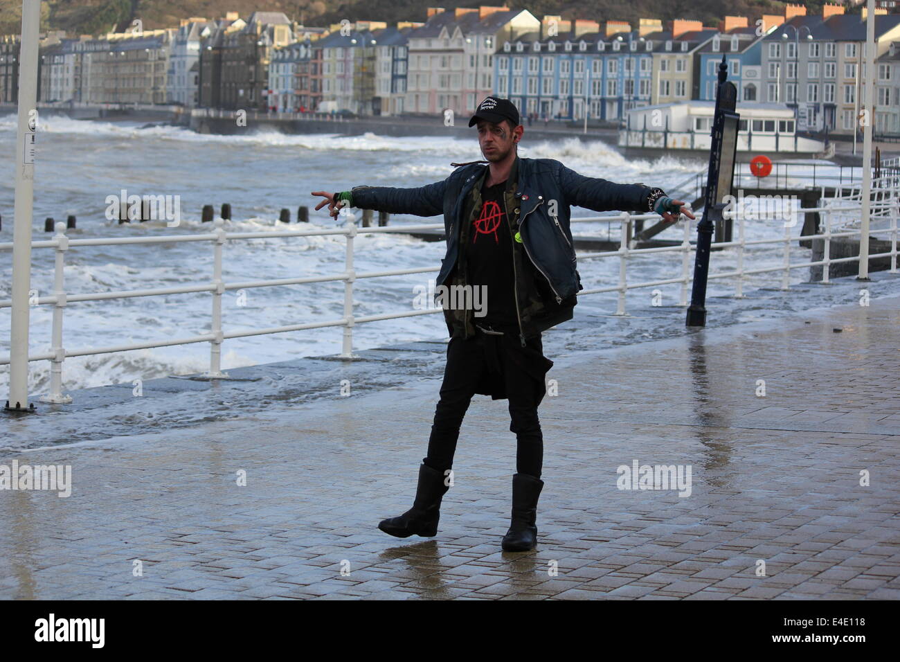 Ein Punk-Stil Mann posiert vor stürmischer See auf Aberystwyth promenade Stockfoto