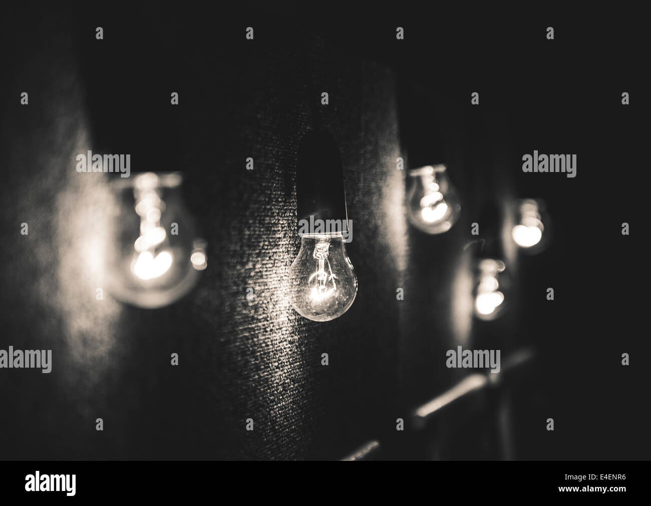 Schwarz / weiß Foto von fünf Glühbirnen gegen einen schwarzen strukturierten Hintergrund. Stockfoto