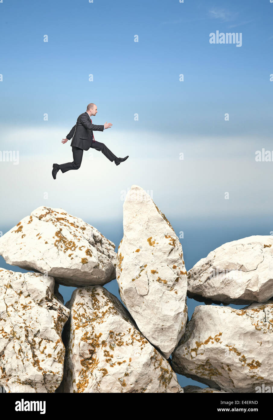 Geschäftsmann Sprung über riesige Felsen Stockfoto