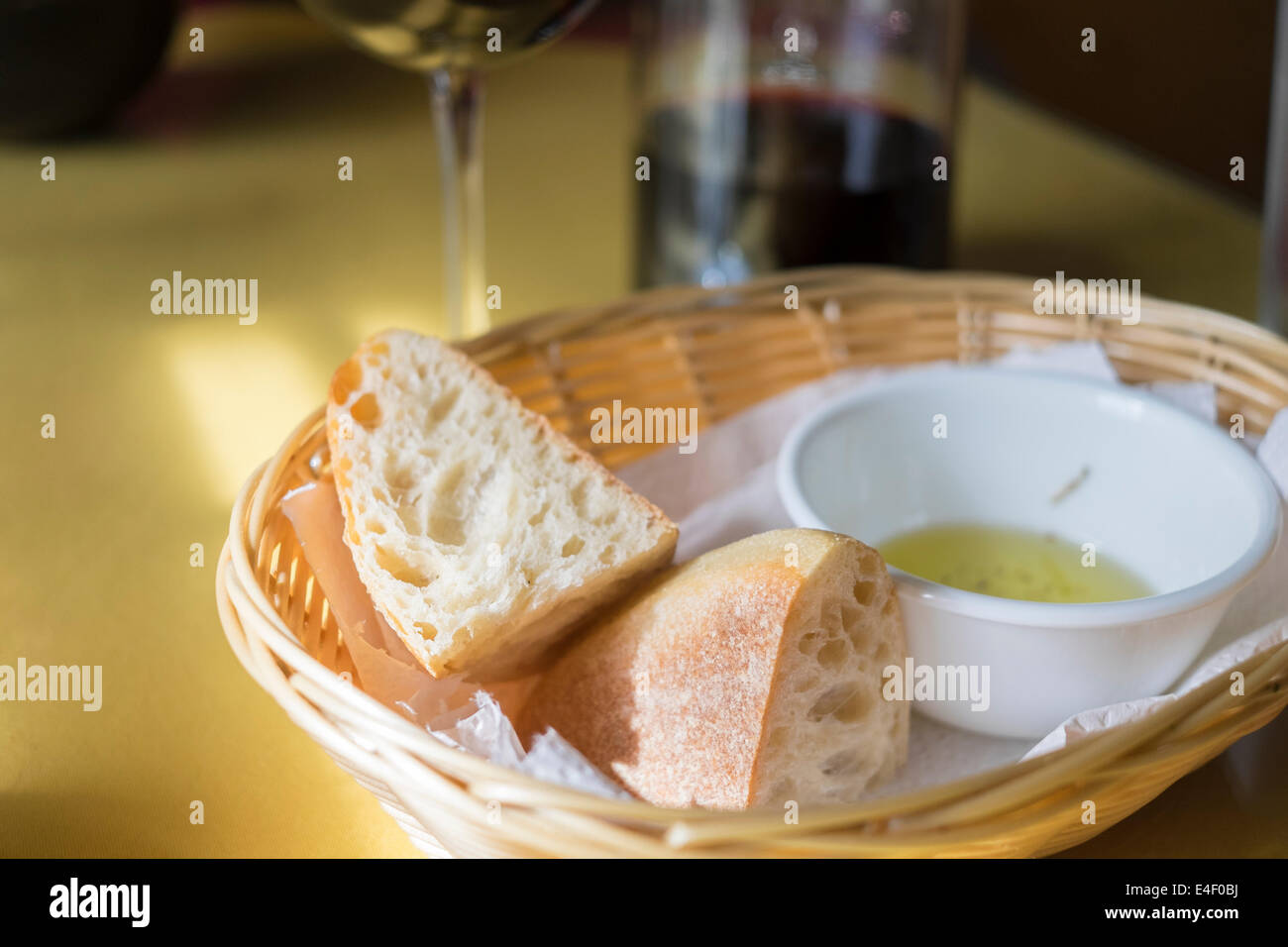Italienisches Essen Tischdekoration mit Ciabatta-Brot, eine Schale mit Knoblauch-Olivenöl und Rotwein im Hintergrund. Stockfoto