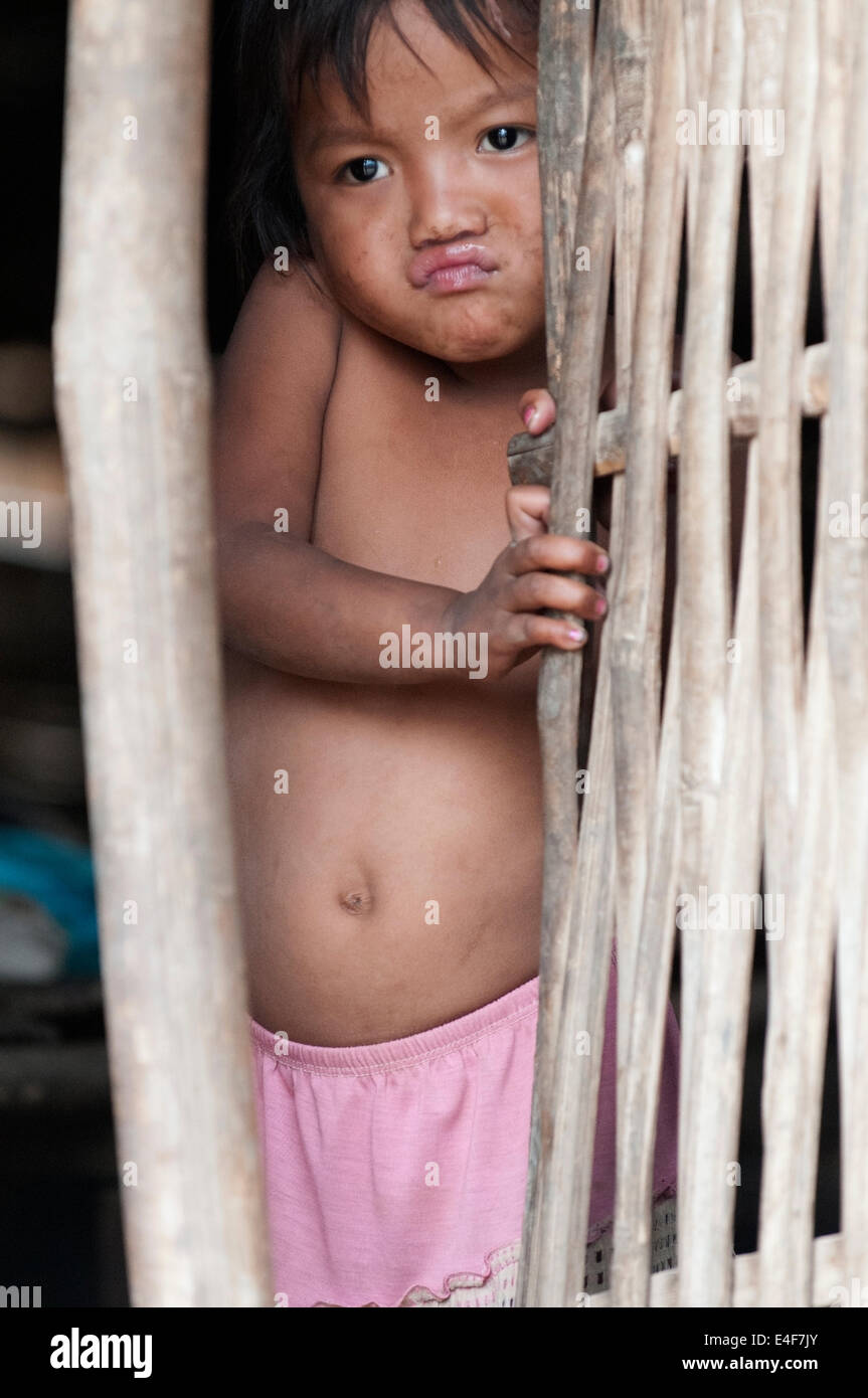 Junges Mädchen versteckt sich in ihrem Haus in einem Dorf auf dem Mekong, Laos. Stockfoto